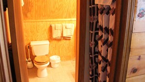 Une salle de bain en bois équipée de toilettes, d’un bidet et d’une petite poubelle.