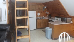 Une cuisine de taille réduite, dotée de meubles de rangement en bois, d’un réfrigérateur, d’une cuisinière et d’un four à micro-ondes.