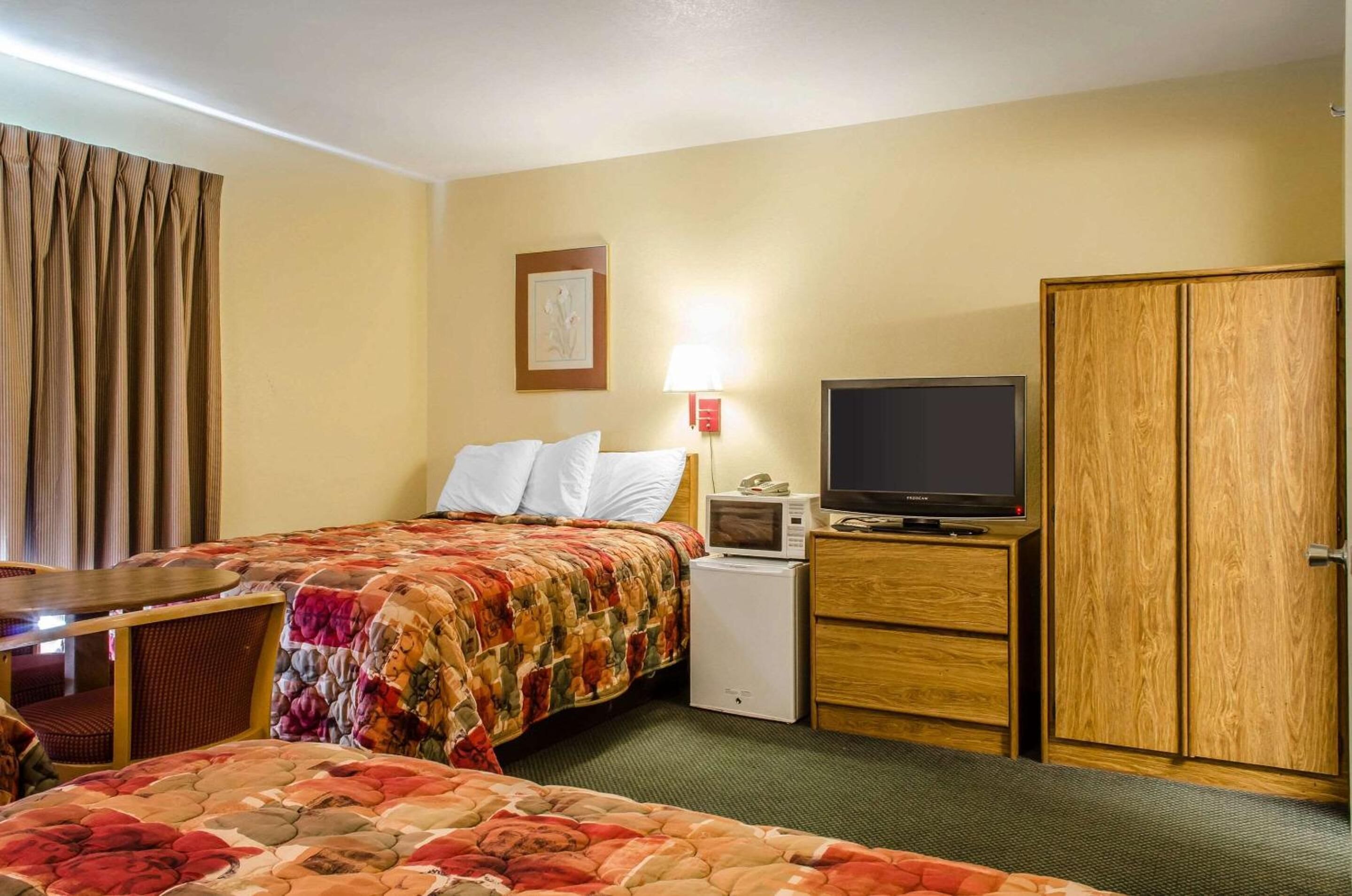 A hotel room with a bed, a TV, a desk, and a wardrobe.