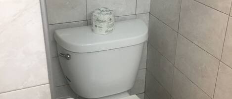 Un baño pequeño y funcional con un inodoro blanco, un dispensador de papel higiénico y un rollo de papel.