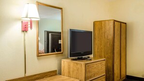 A hotel room with a wooden desk, a television on a wooden stand, a mirror, and a wardrobe. - Relax Inn (Lewisburg)