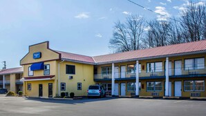 A motel with a yellow facade, a red roof, and a blue sign.