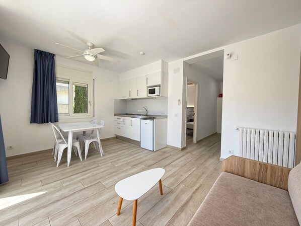 A modern kitchen with white cabinets, a microwave, and a dining area with a white table and chairs. - Agi Rescator 206 Apartamento for rent in Roses Girona. (Rosas / Roses)