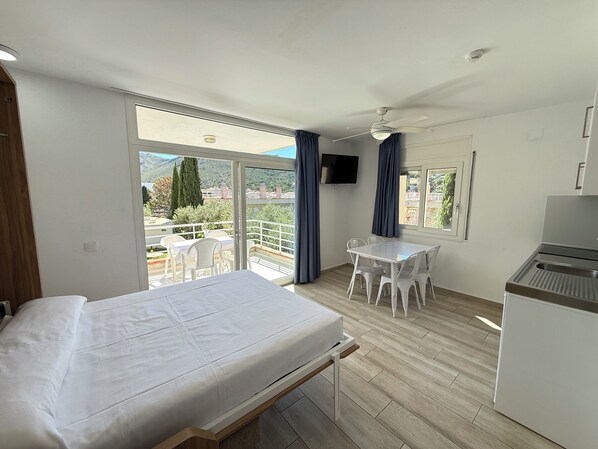 Une chambre avec un lit, une petite table, une télévision et un balcon avec vue.