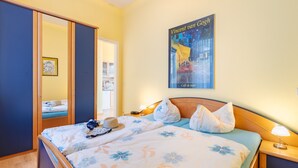 A hotel room with a bed, a nightstand, a lamp, a poster of Vincent van Gogh, and a wardrobe.