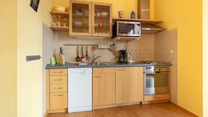 A kitchen with wooden cabinets, a microwave, an oven, and a dishwasher.