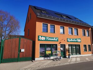 Een gebouw met twee verdiepingen, met een rode gevel, en borden met 'Ferienhof' en 'Rädlerslust'.