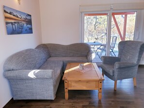 Een woonkamer met een hoekbank, een houten salontafel en een fauteuil.