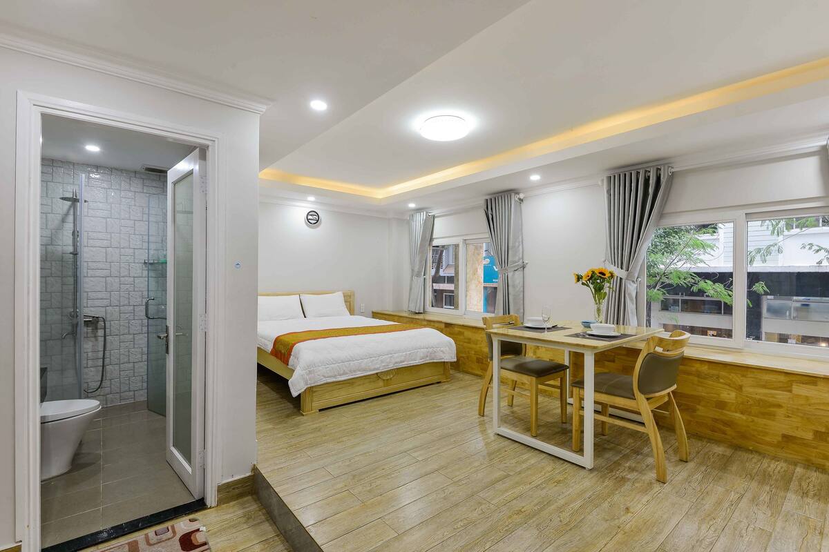 Hotelkamer met een bed, een bureau met stoel, een douche en een raam met uitzicht.