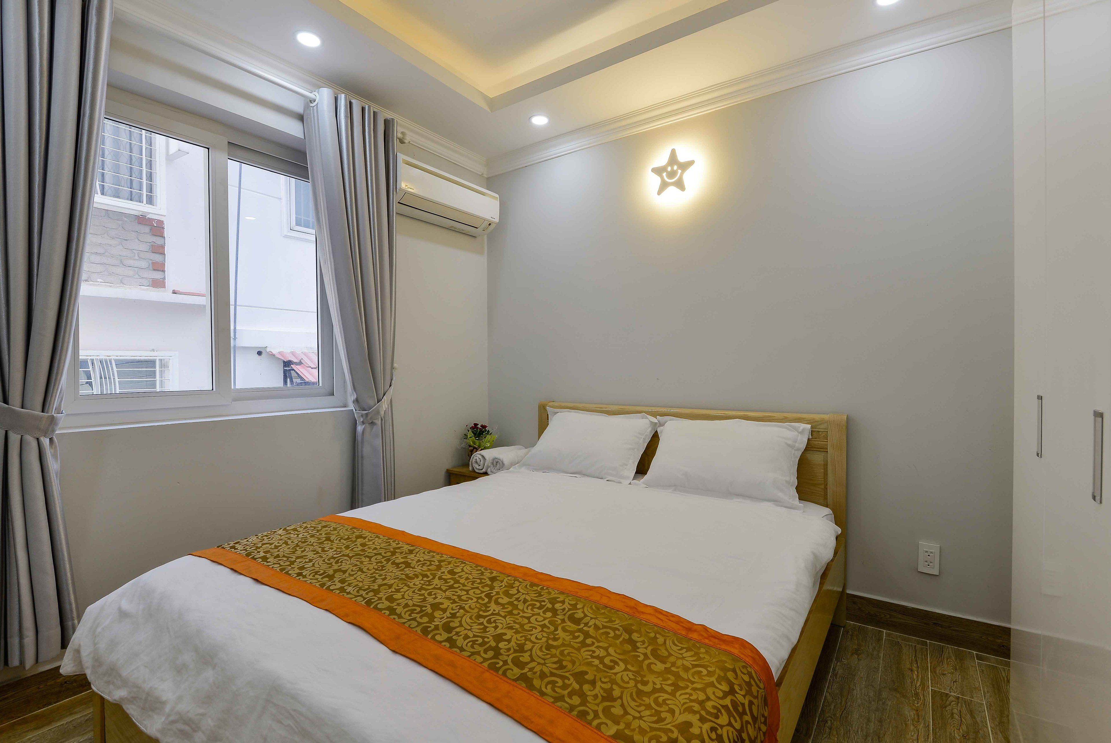 A neatly made bed with a patterned bedspread and a star-shaped light fixture on the wall.