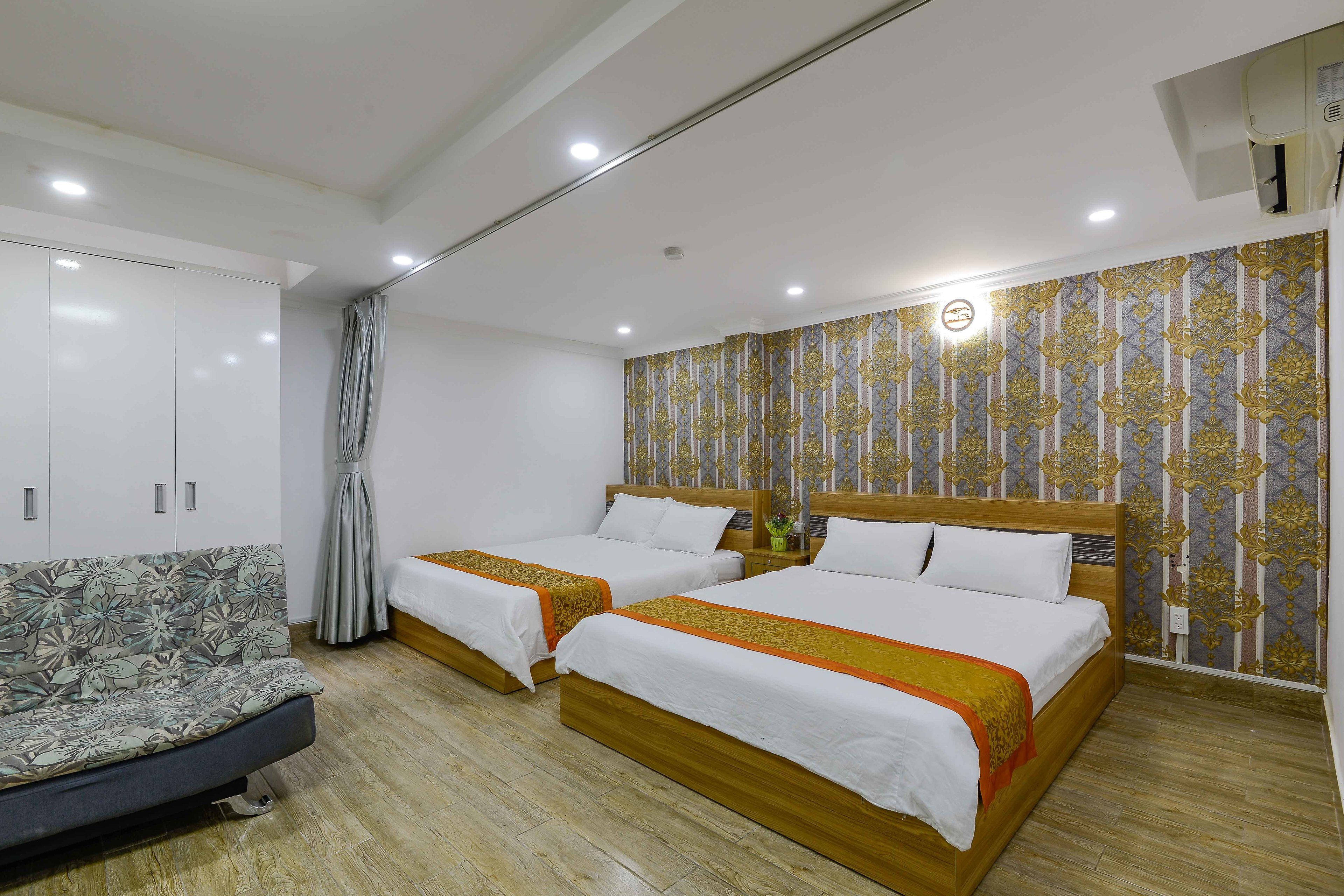 Une chambre d’hôtel avec deux lits, un canapé et une armoire.