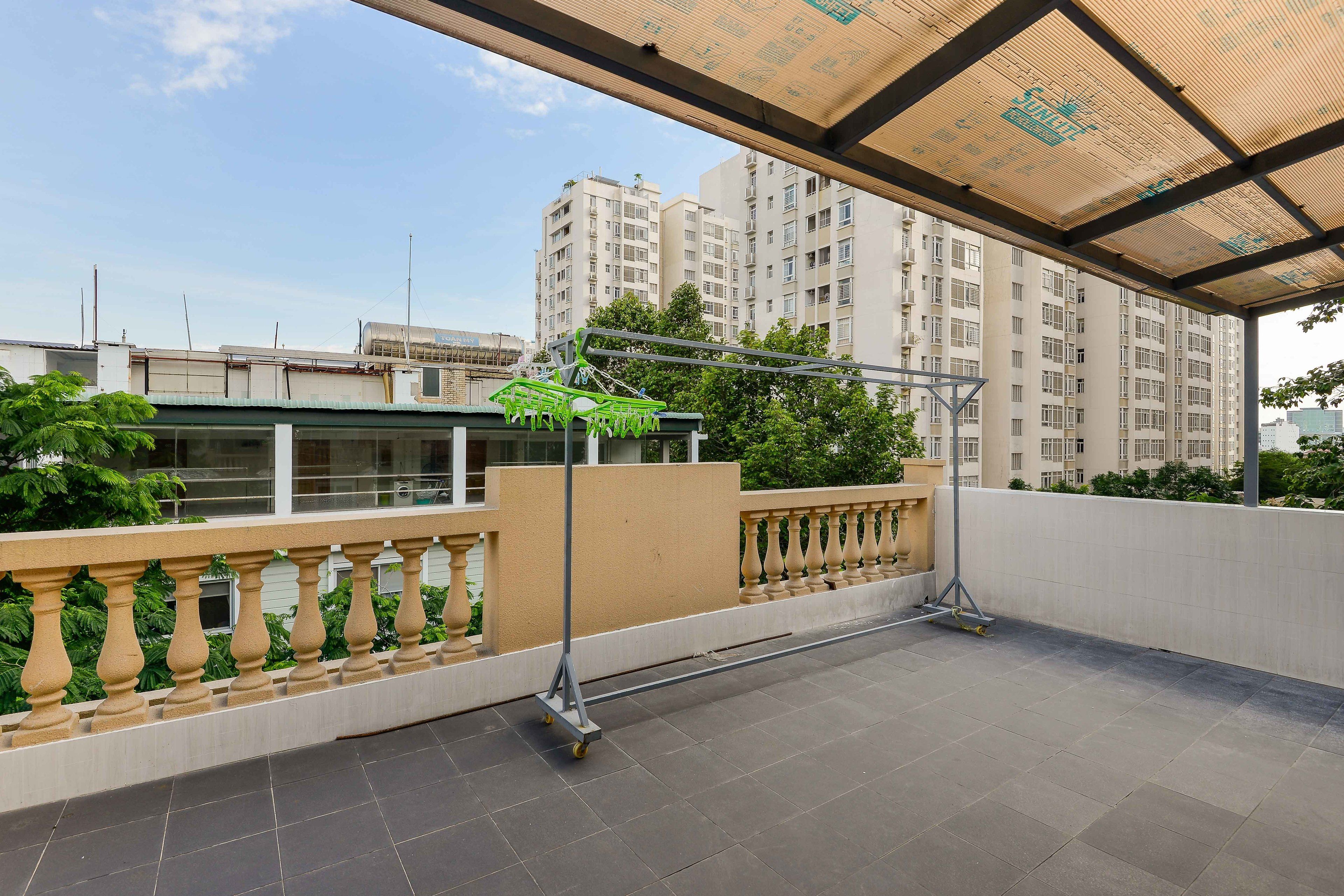 Una terraza en la azotea con barandilla de metal, una pérgola y vistas a edificios altos.