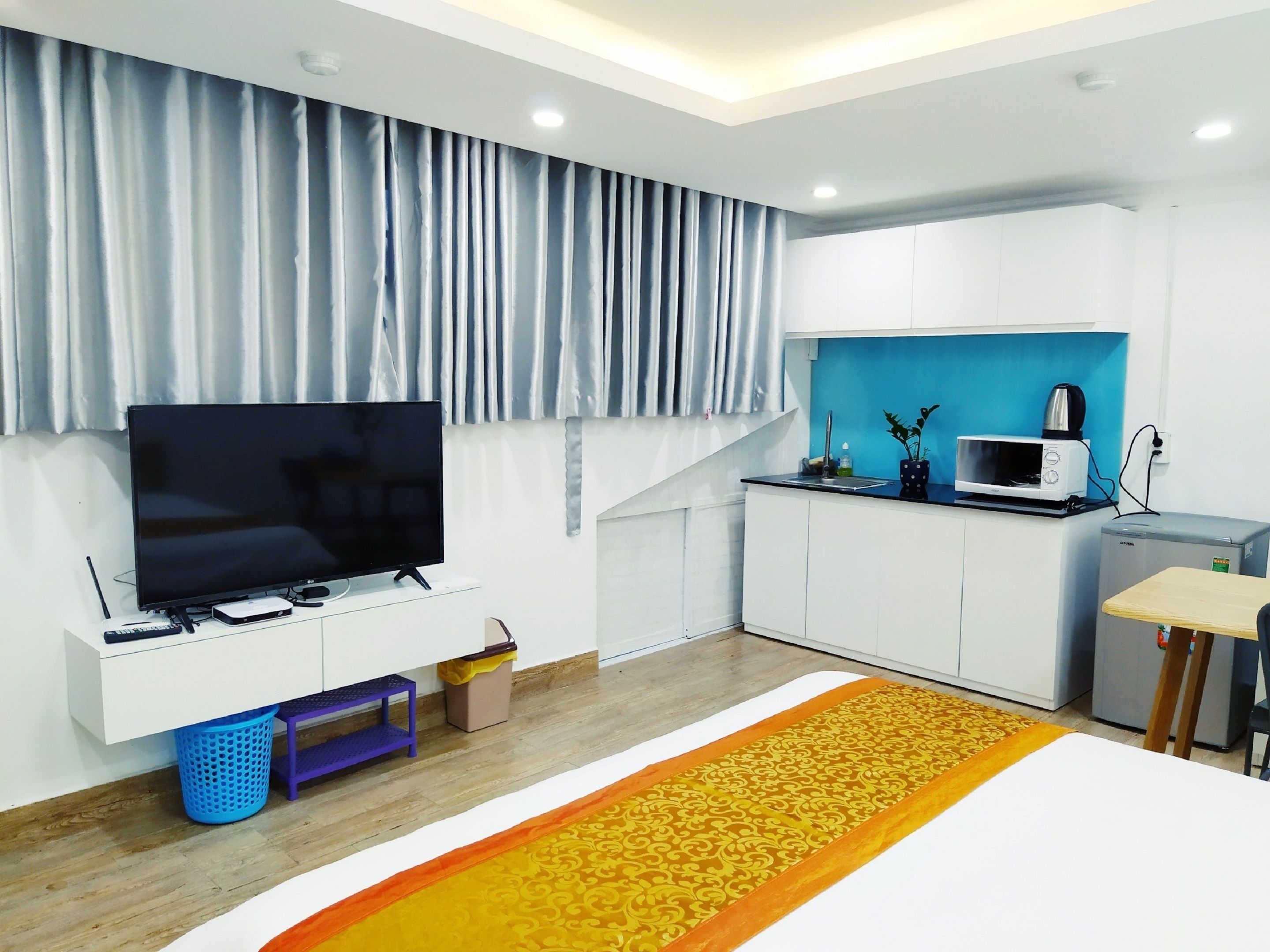 A modern kitchen with white cabinets, a microwave, and a small table.