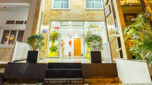 A hotel with a sign for 'Melody Apartment' and a visible entrance with steps leading to the door.