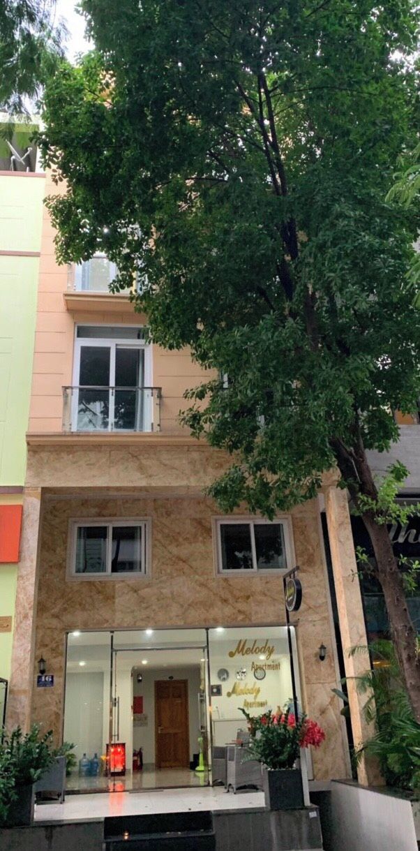A building with a glass entrance, a sign reading 'Moleyy Apartment,' and a tree in front.