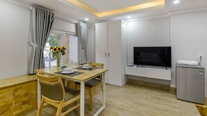 A modern room with a dining table, chairs, a flat-screen TV, a refrigerator, and a window with curtains.