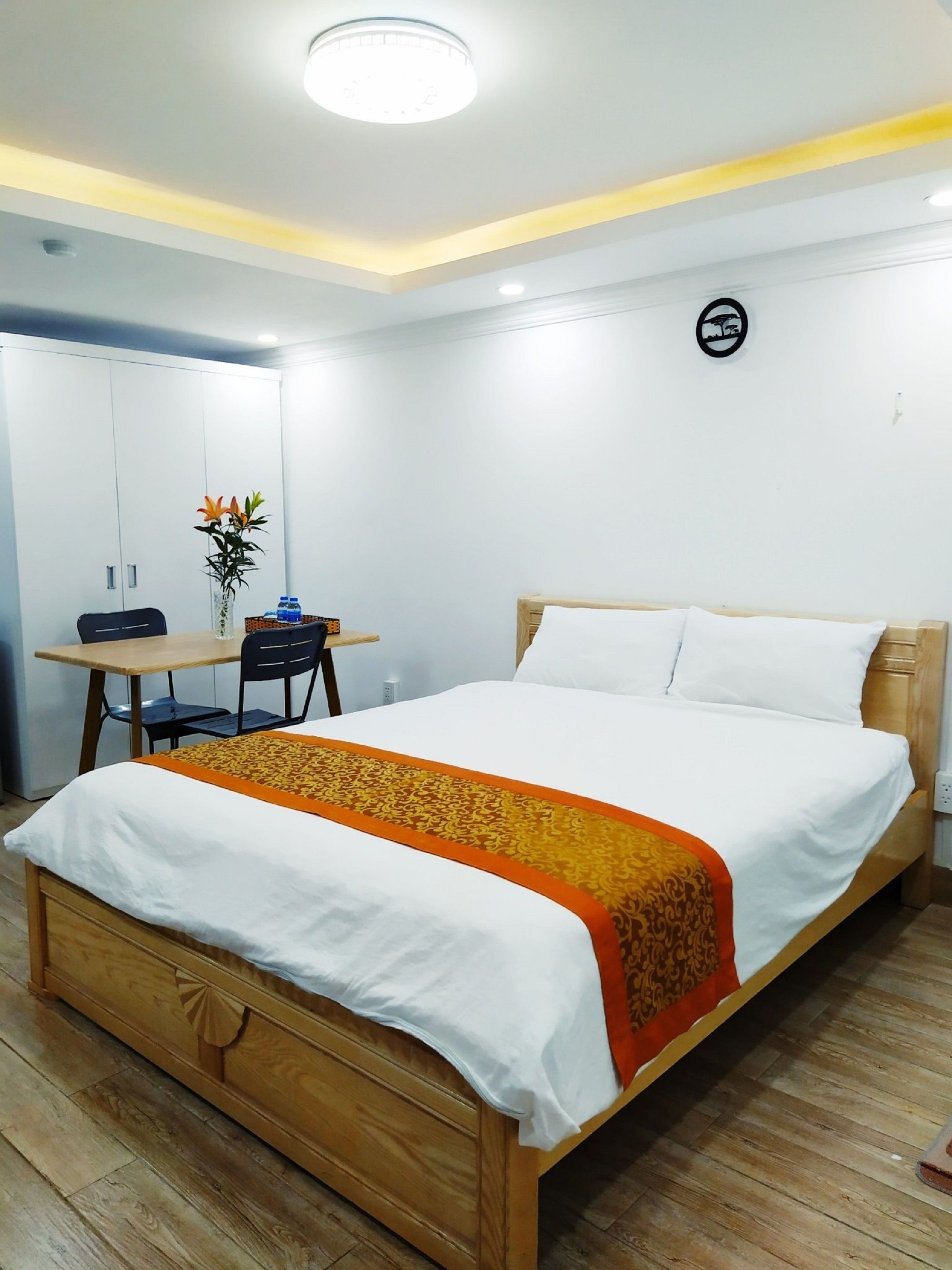 A neatly arranged bedroom with a wooden bed, a small desk, and a chair.