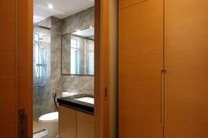 Un bagno moderno con box doccia in vetro, un water bianco e un piano d'appoggio nero con uno specchio sopra il lavandino.