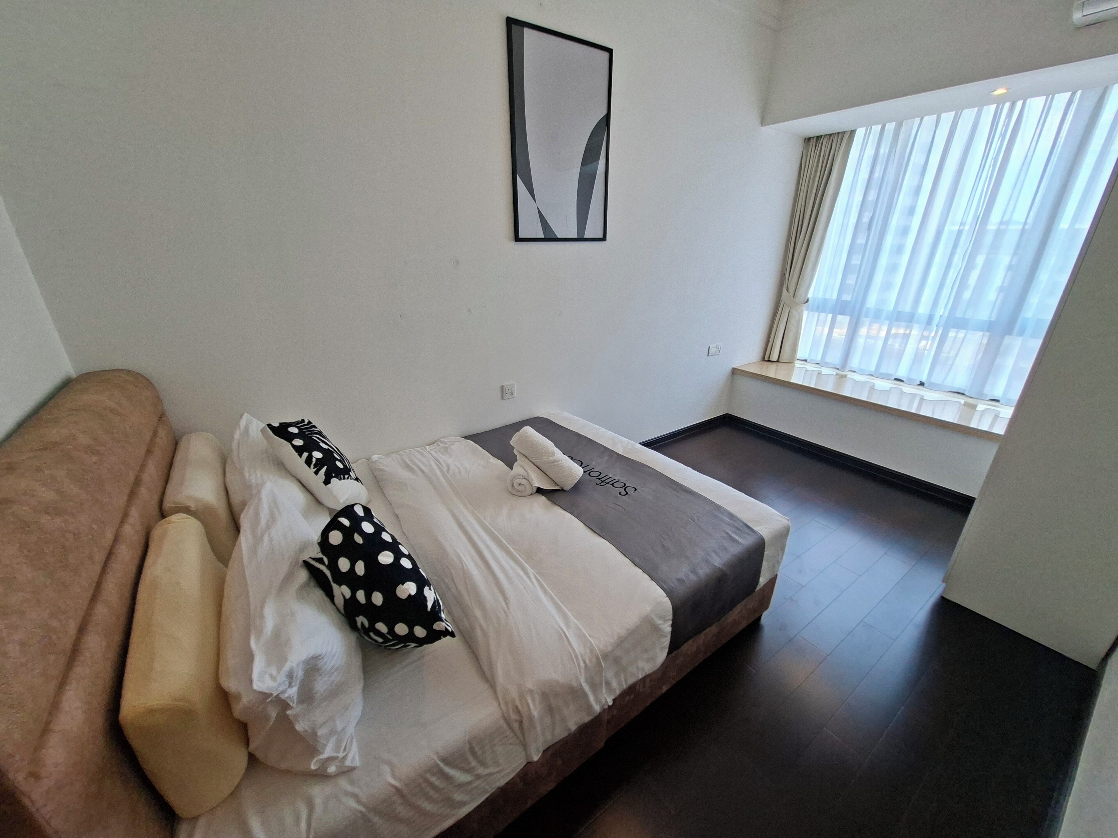 Una habitación de hotel moderna con una cama, un sofá marrón y una ventana con cortinas.