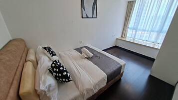 Una habitación de hotel moderna con una cama, un sofá marrón y una ventana con cortinas.