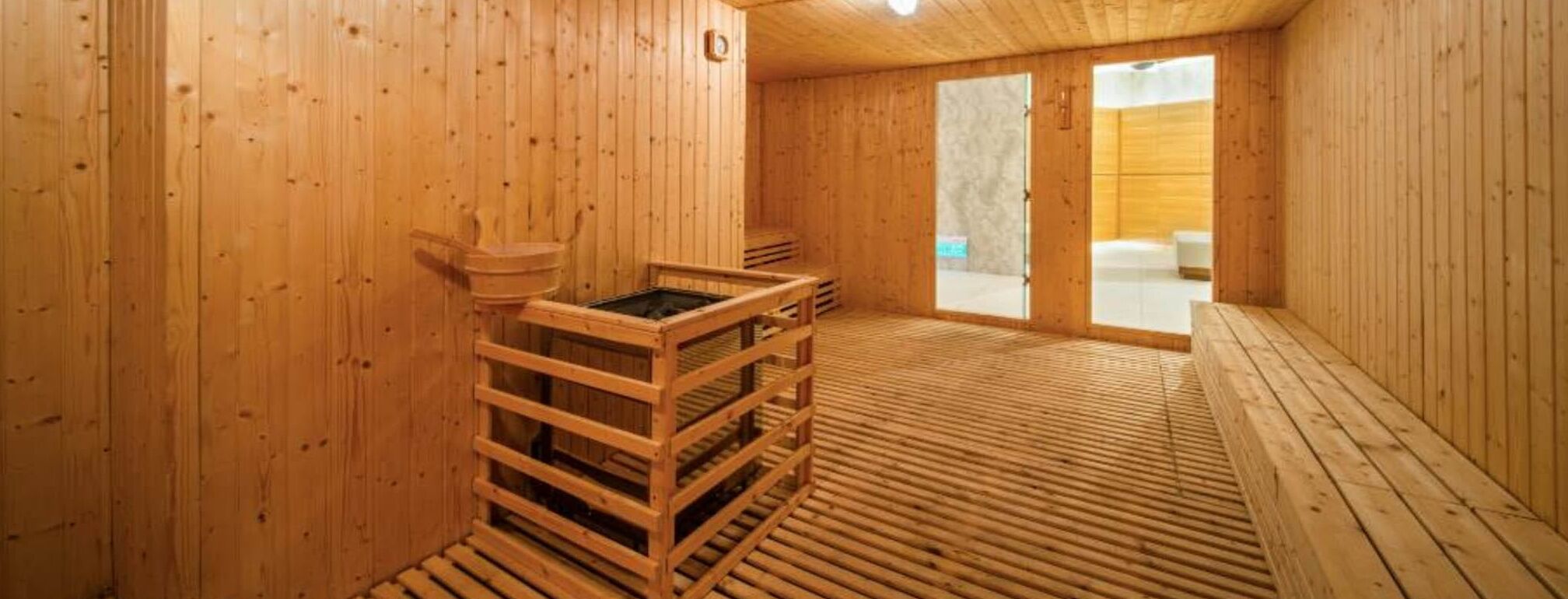 A wooden sauna room with a bench, a wooden sauna table, and a window.