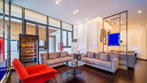 A modern living room with glass walls, a red chair, two sofas, and a flat-screen TV. - R&F Princess Cove JB By SaffronCasa JB (Johor Bahru)
