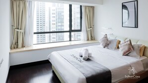 A hotel room with a large window, a bed with a towel, and a framed picture on the wall. - R&F Princess Cove JB By SaffronCasa JB (Johor Bahru)