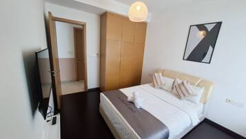 Habitación de hotel con cama, armario, espejo, televisor y una lámpara colgante.
