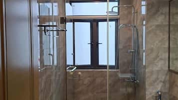 A modern bathroom with a glass-enclosed shower, a toilet, and a sink.