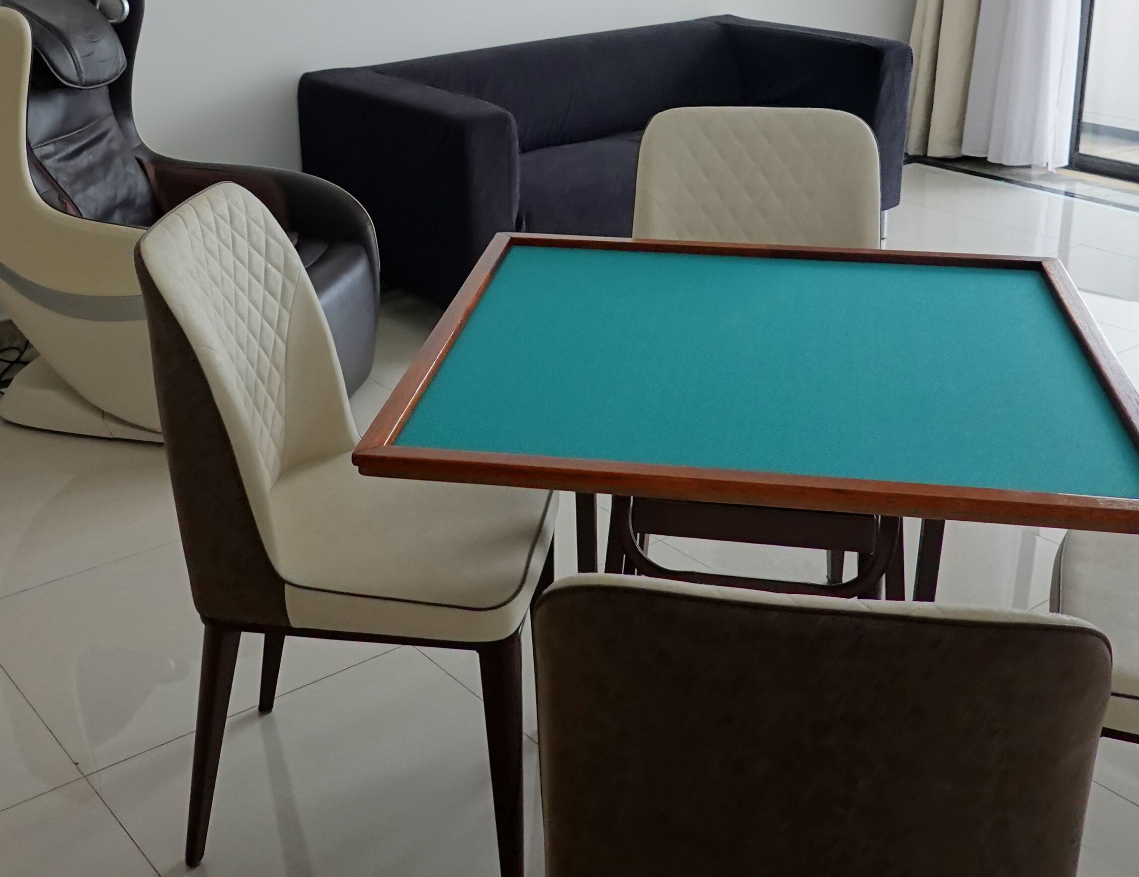 A pool table with four chairs, a sofa, and a leather chair in a room with a tiled floor.