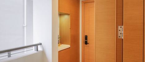 Un baño moderno con tocador de madera, un espejo y una puerta con pomo.