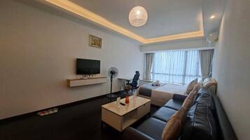 A modern living room with a sofa, a coffee table, a TV, and a ceiling light fixture.