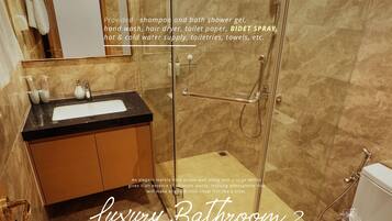 A luxury bathroom with a marble-tiled accent wall, a large mirror, and a glass-enclosed shower.
