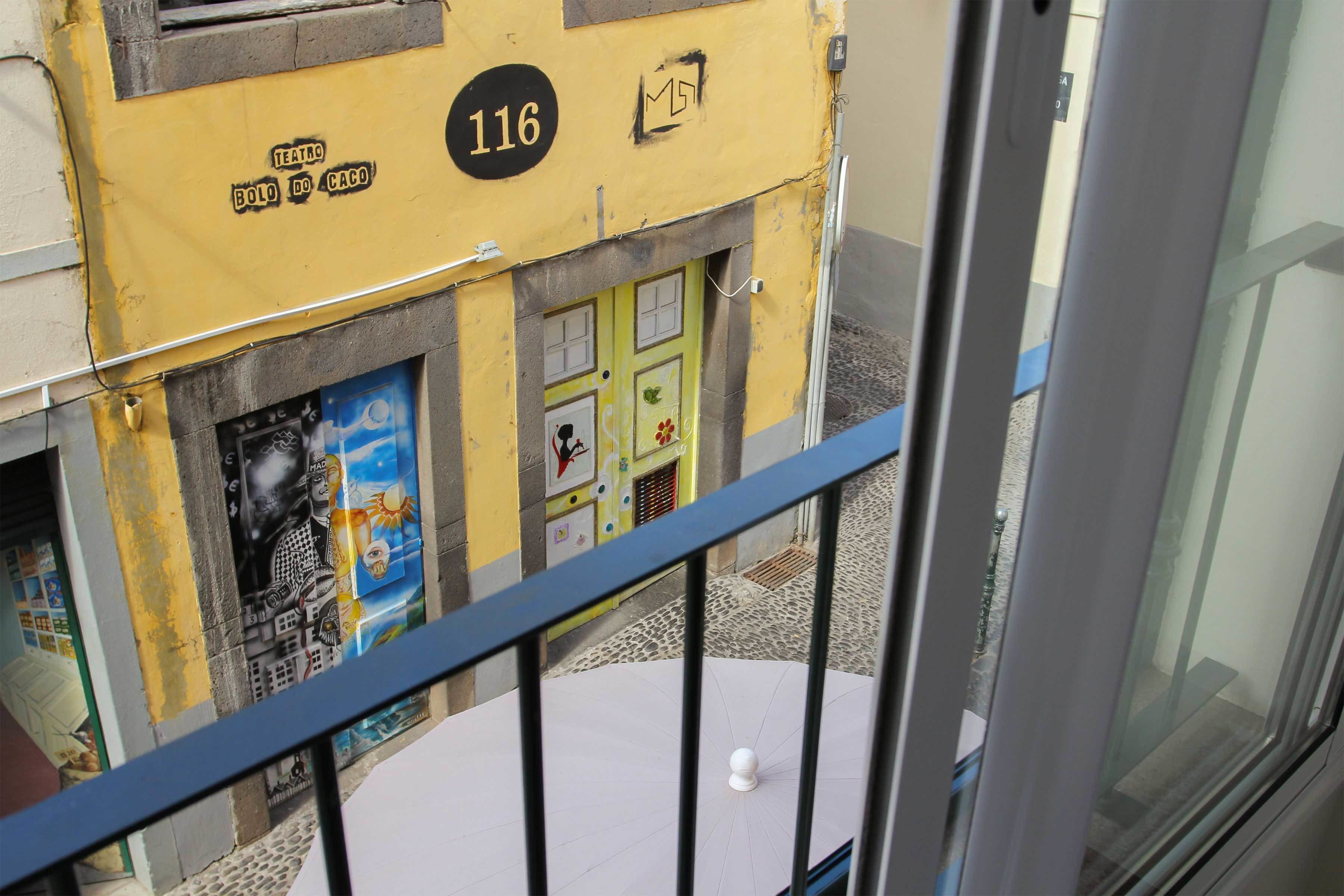 A yellow building with the number 116 and a sign that reads "Teatro Bolo do Caco".