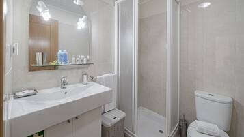 A bathroom with a sink, mirror, shower, and toilet.