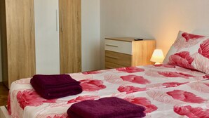 A bedroom with a bed, a wardrobe, a bedside table with a lamp, and a floral bedspread. - DayDream (Pomorie)