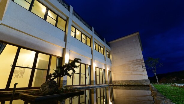 A modern building with large windows and a reflective water feature in front. - Yasengawa (Hengchun)