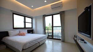 A modern hotel room with a large bed, a flat-screen TV, an air conditioning unit, and a balcony with a view. - Yasengawa (Hengchun)