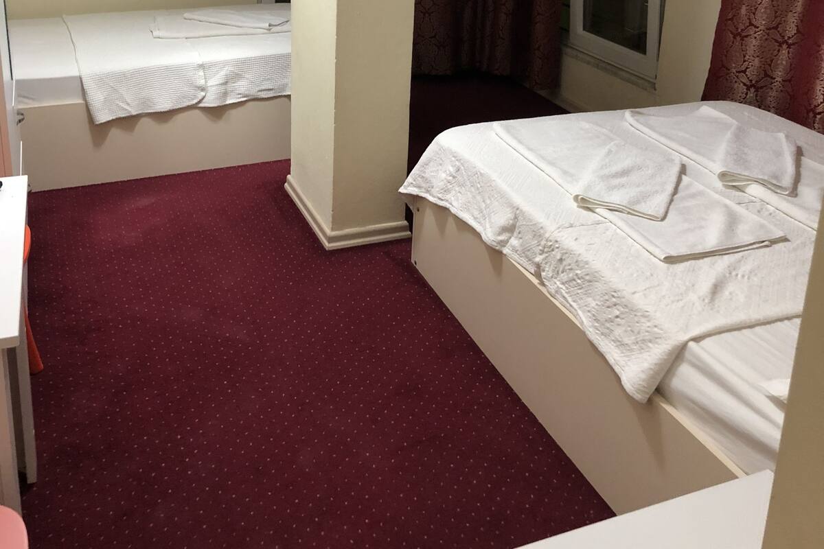 A hotel room with a bed, a desk, and a television mounted on the wall.
