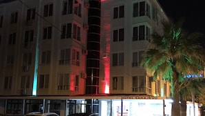 A multi-story hotel with a central tower, balconies, and a palm tree in the foreground. - Hotel Sarayevo (Ayvalik)