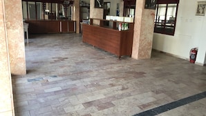 A spacious lobby with a reception desk, tiled flooring, and various framed pictures on the walls. - Hotel Sarayevo (Ayvalik)