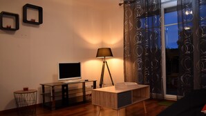 Ett modernt vardagsrum med en platt-TV, en lampa och ett träbord.