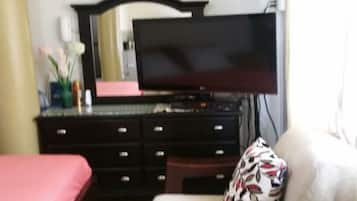 Una habitación de hotel con una cama, televisión, cómoda y sofá.
