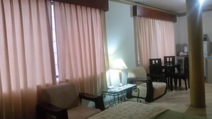A living room with a sofa, a small table with a lamp, and a dining area with chairs and a table. - Casa Serena (Guayaquil)