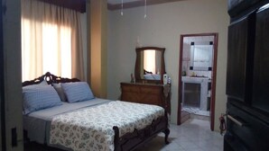 A bedroom with a bed, dresser, mirror, and a door leading to a bathroom. - Casa Serena (Guayaquil)