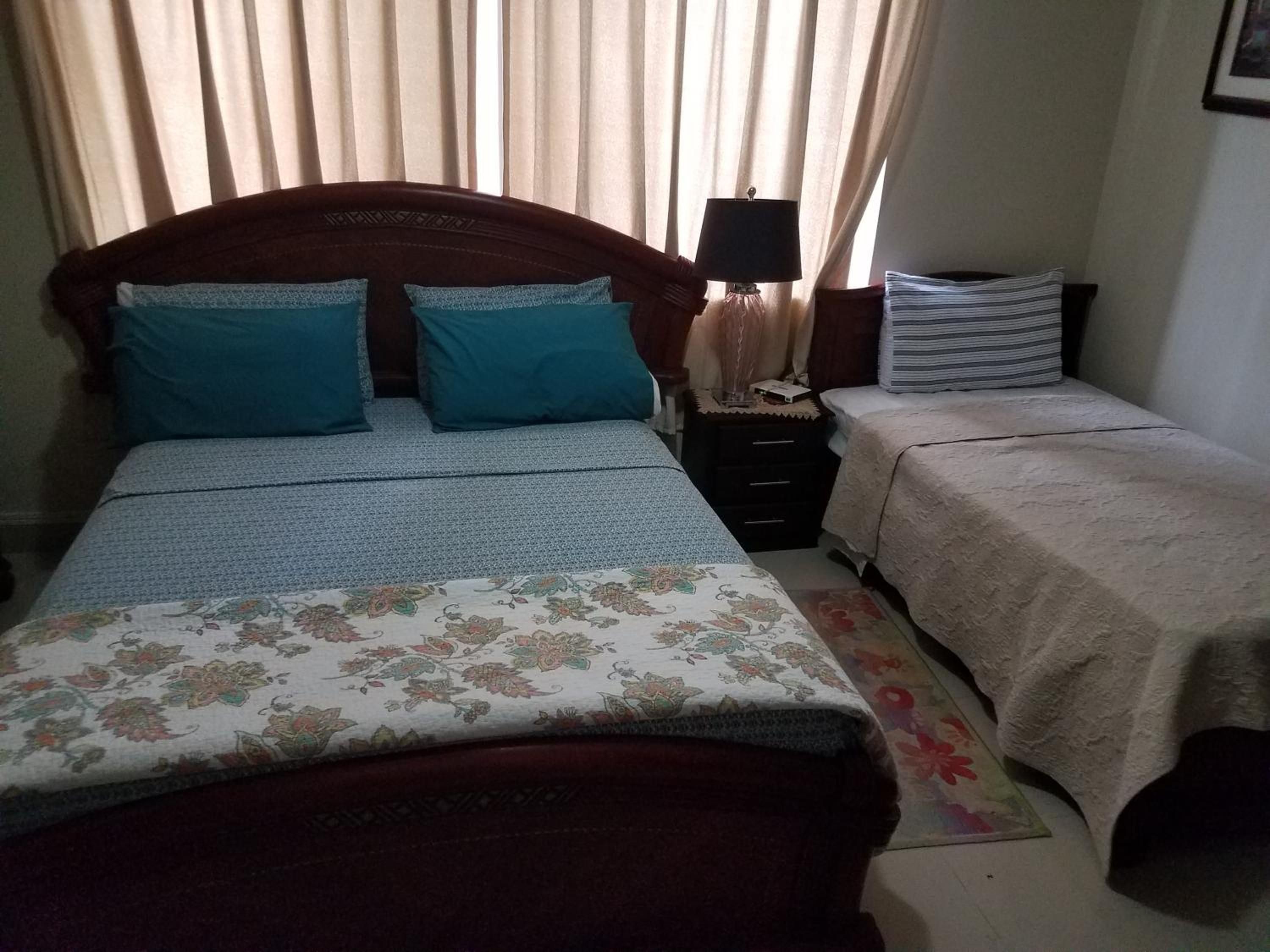 A bedroom with a large bed, two bedside tables, a lamp, and a small table with a lamp.