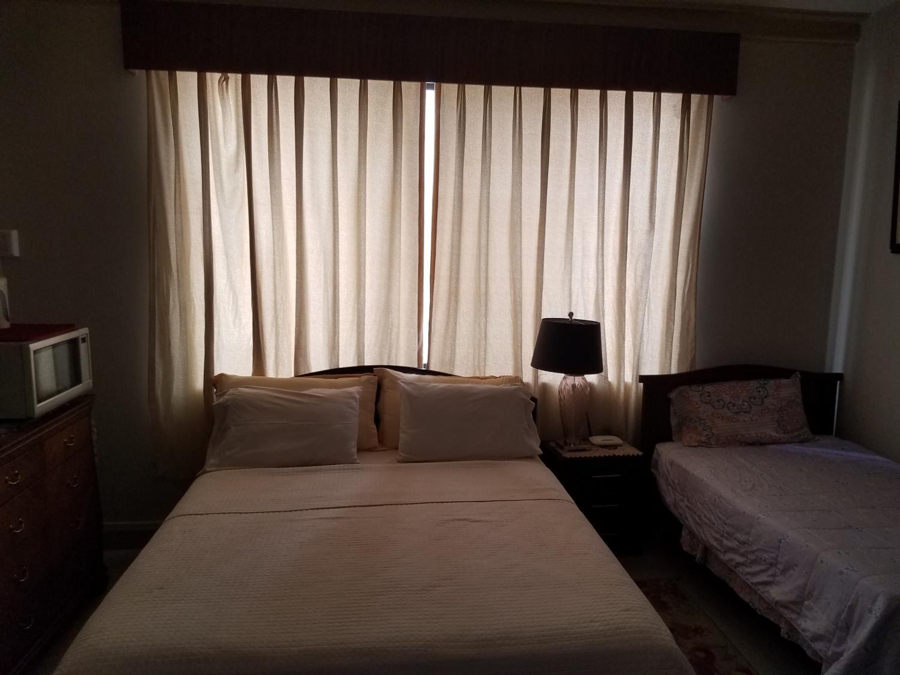Een hotelkamer met een bed, nachtkastje met lamp, televisie en een dressoir.