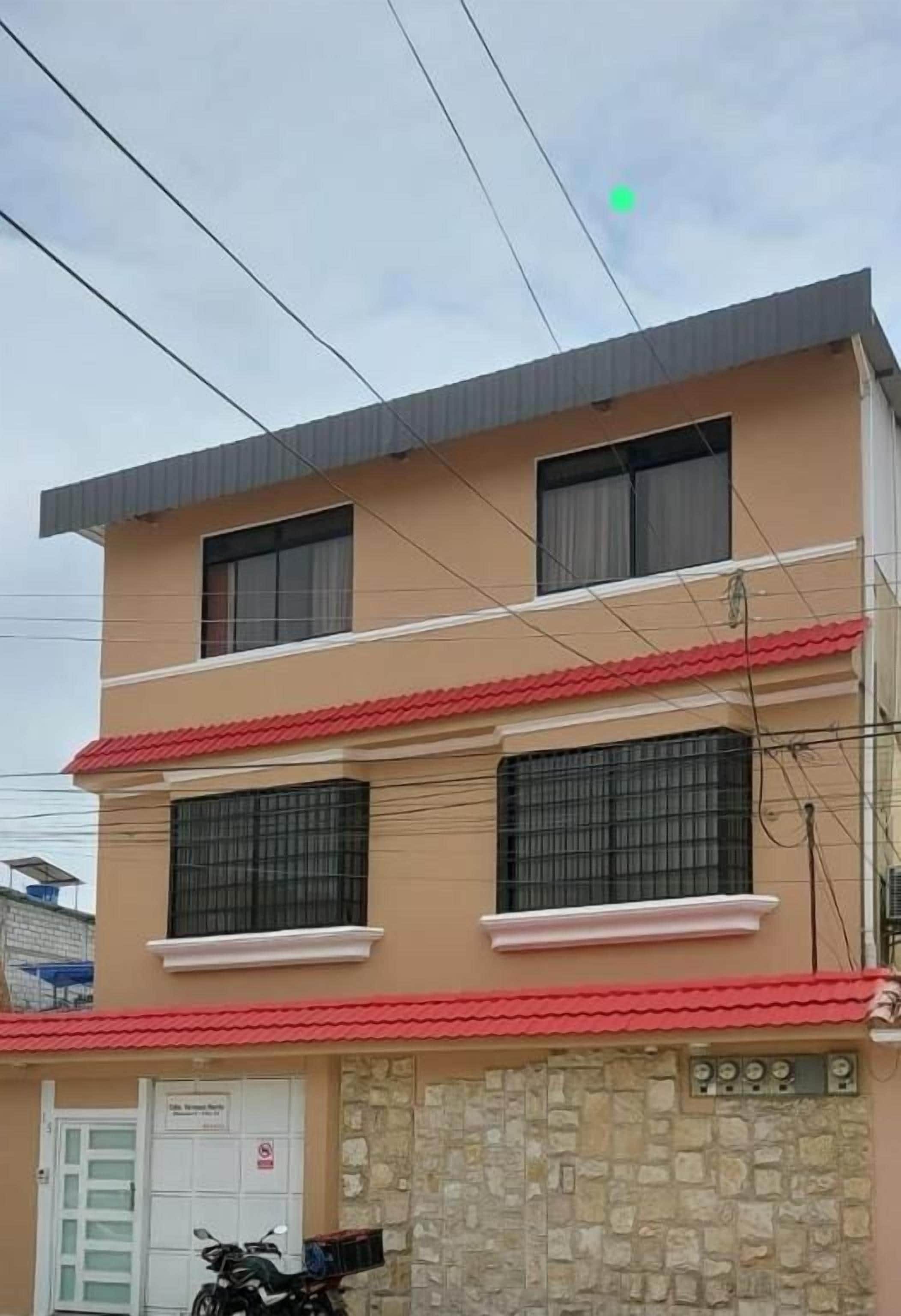 A multi-story building with a flat roof, two visible windows on the ground floor, and a stone facade.