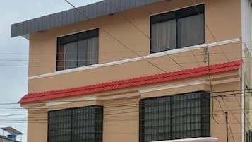 A multi-story building with a flat roof, two visible windows on the ground floor, and a stone facade.