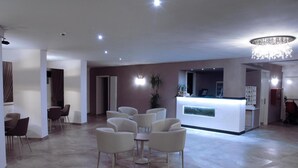 A spacious lobby with a reception desk, seating area, and a chandelier. - Hotel Schiller (Cervia)